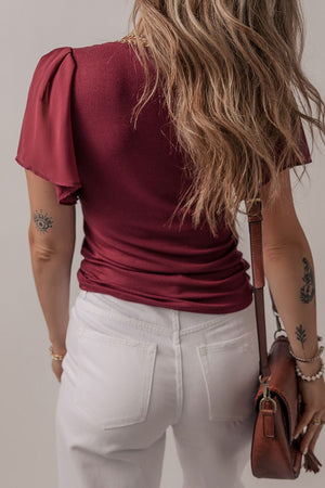 Burgundy ribbed knit top with flutter sleeves and a gold chain detail.