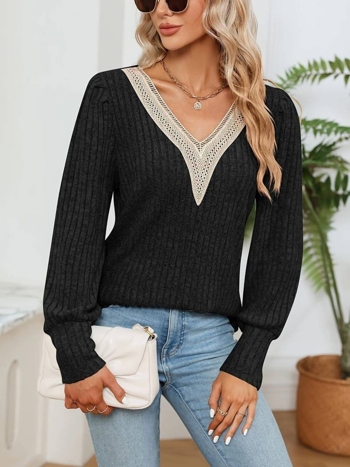 Black ribbed knit sweater with lace trim V-neck and puff sleeves.
