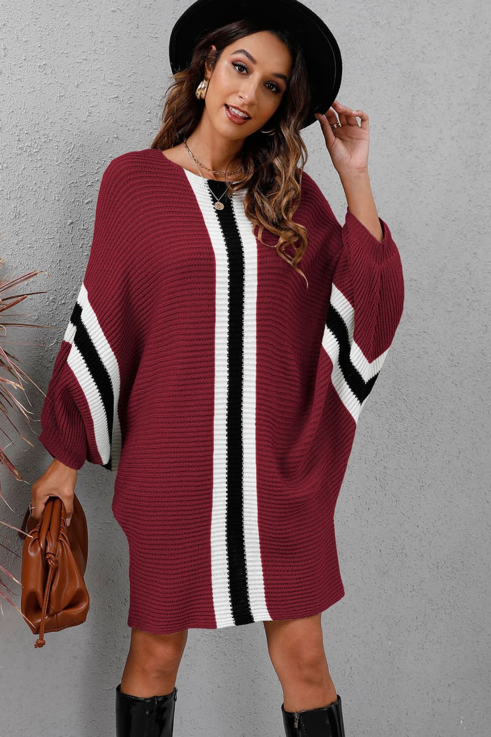 Burgundy oversized knit dress with black and white stripes on sleeves and center panel.