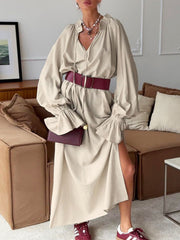 Beige cotton maxi dress with tie neck, ruffled cuffs, and side slit.