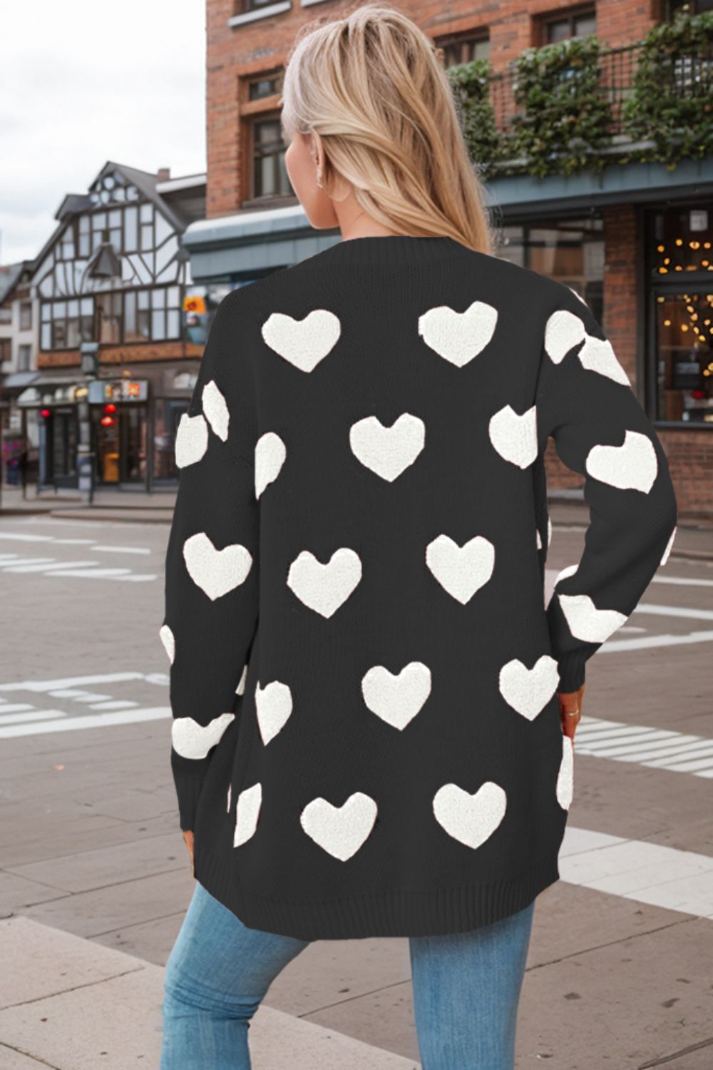 Black acrylic knit cardigan with white heart appliqué pattern.