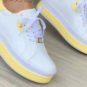 White lace-up platform sneakers with yellow accents and daisy detail.