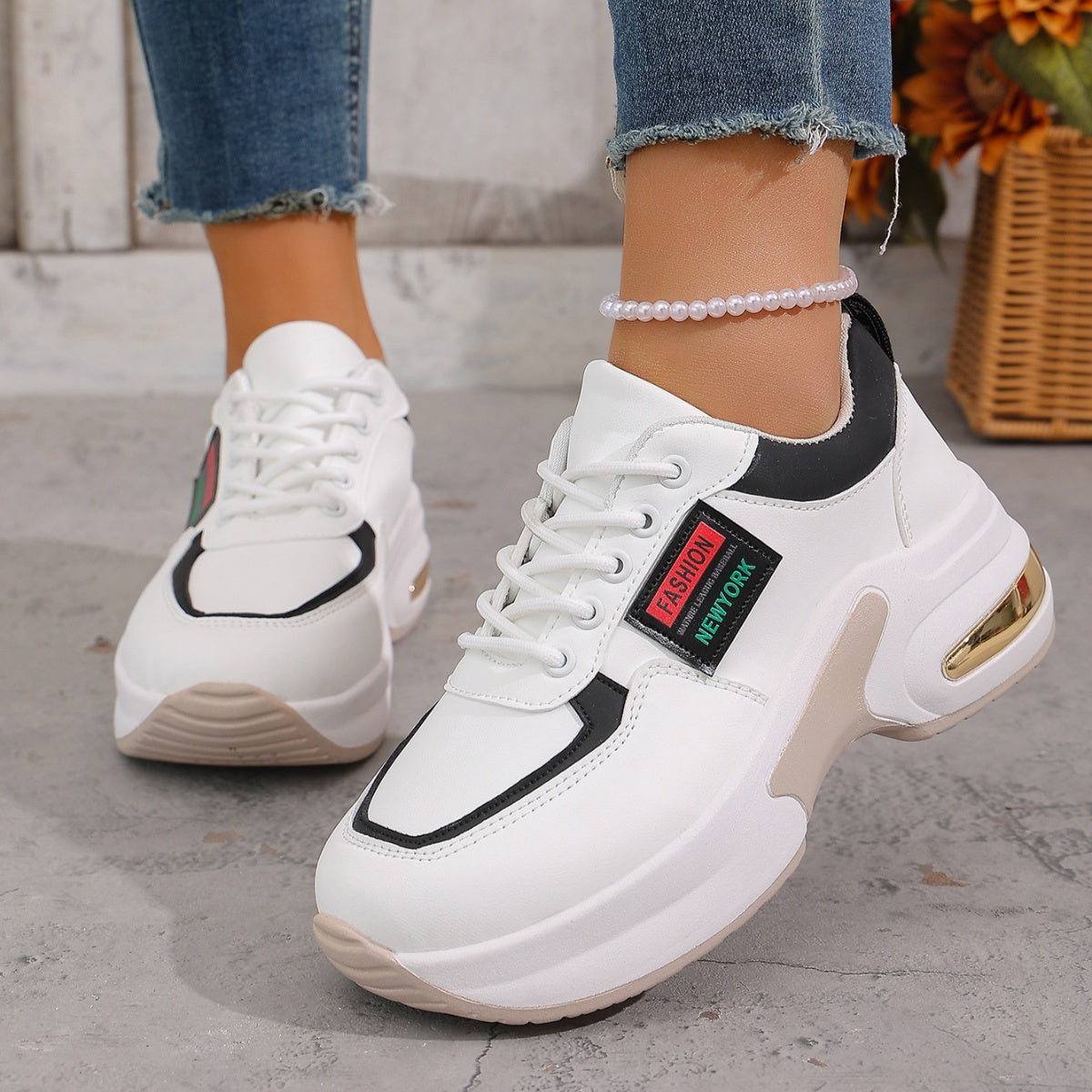 White lace-up sneakers with black and gold accents and a chunky sole.