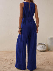 Indigo textured wrap-front wide-leg jumpsuit with belted waist and keyhole back detail.