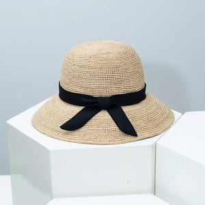 Chic wheat straw sun hat with black bow detail, adjustable.