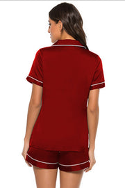 Scarlet satin pajama set with white piping, short sleeves, collared button-up top and shorts.