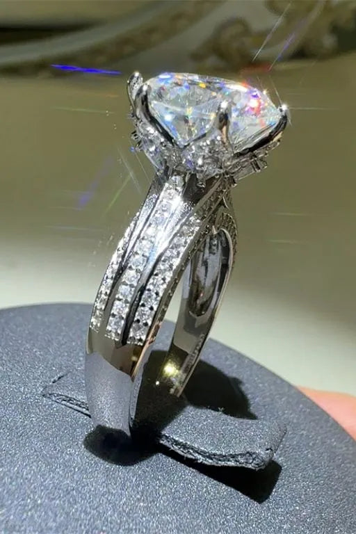 Silver moissanite ring with a large center stone and pave band.
