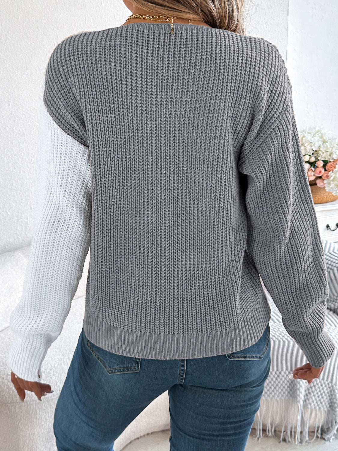 Asymmetrical colorblock knit sweater in gray and white with button detail.