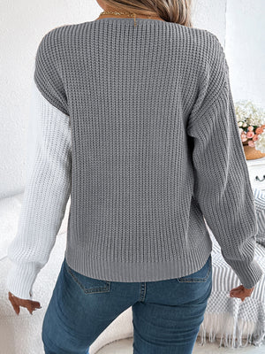Asymmetrical colorblock knit sweater in gray and white with button detail.