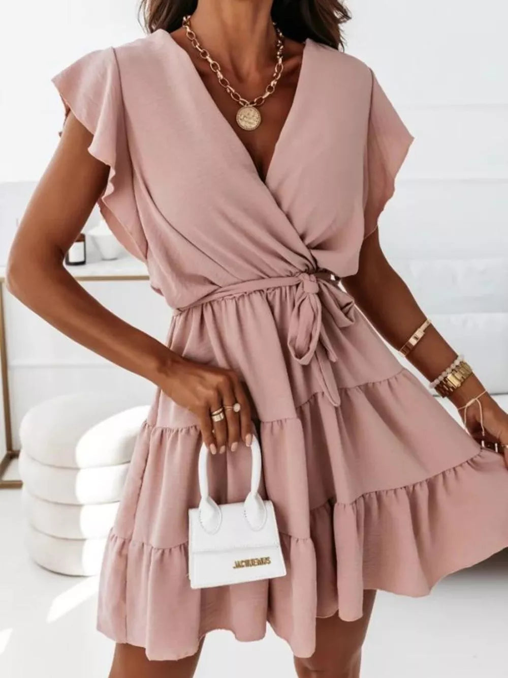 Dusty pink polyester mini dress with ruffle sleeves, V-neck, tie waist, and tiered skirt.