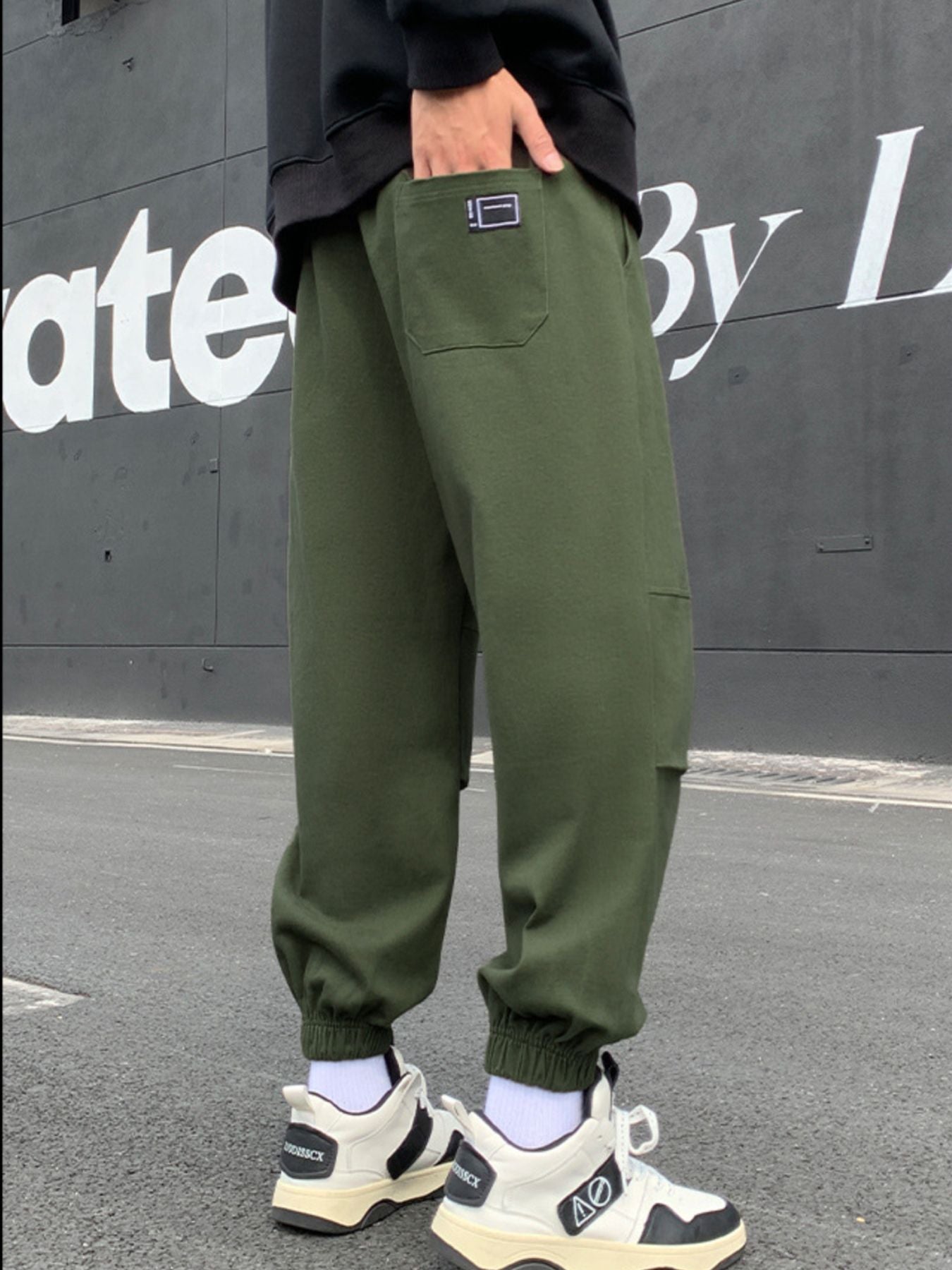 Army green relaxed fit joggers with pockets and elastic cuffs, worn by a man.