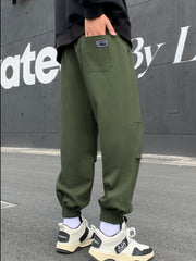 Army green relaxed fit joggers with pockets and elastic cuffs, worn by a man.