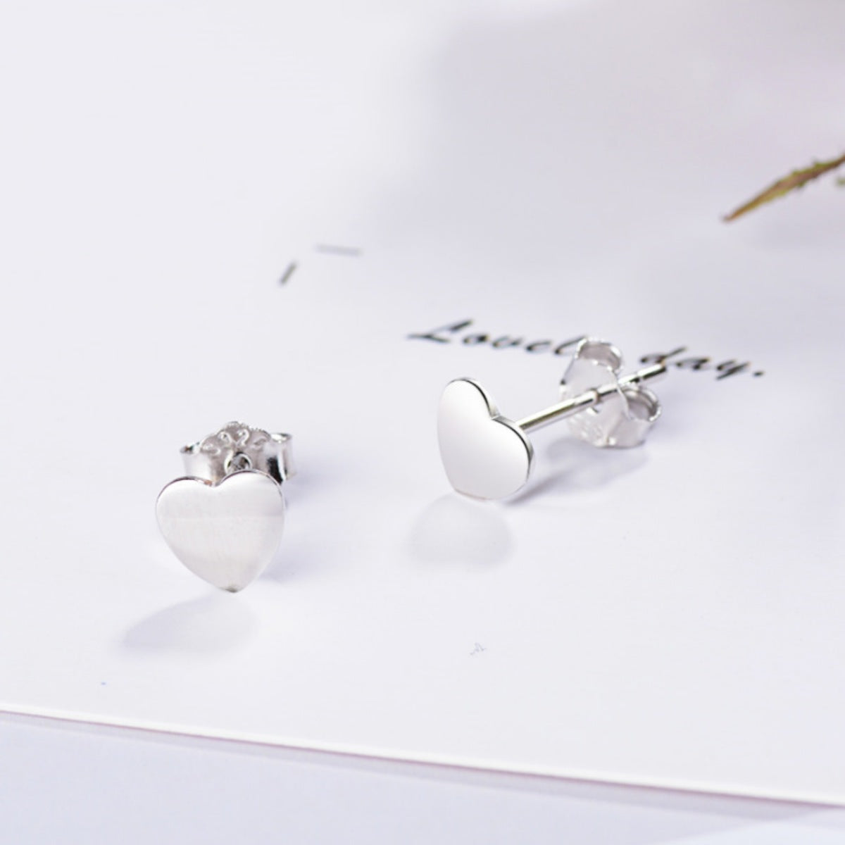 Elegant heart-shaped sterling silver stud earrings with butterfly backs.