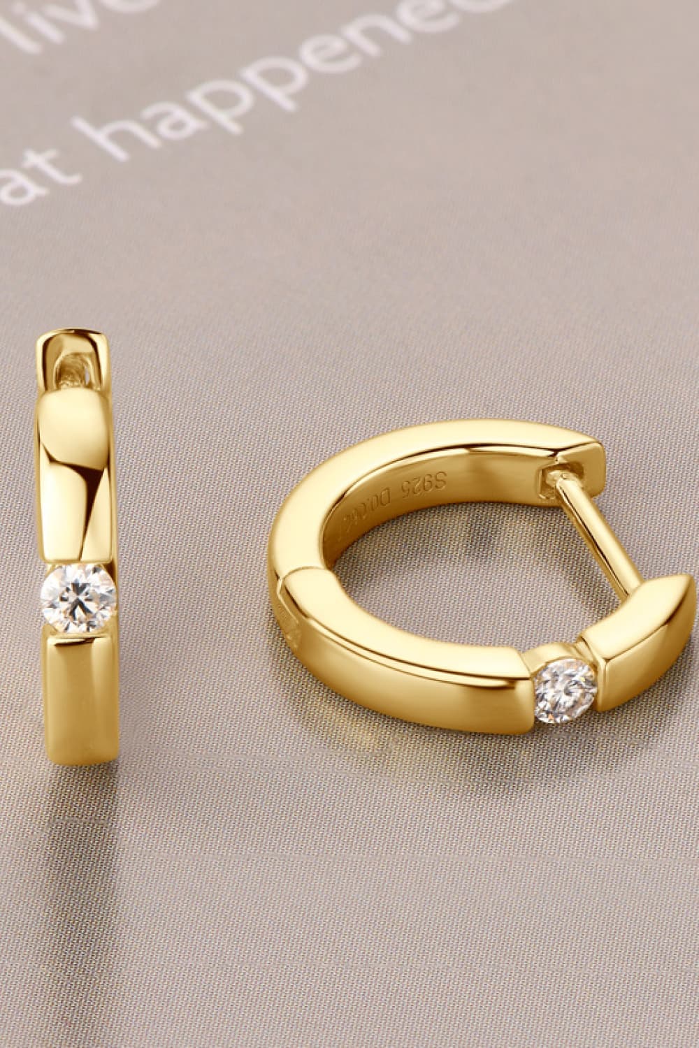 Gold pavé point huggie hoop earrings with a single clear stone detail.