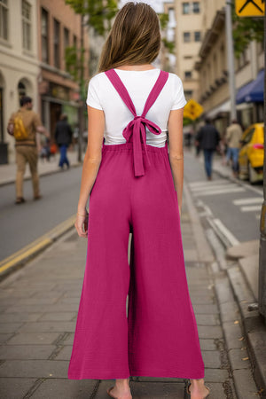 Gathered bib wide-leg jumpsuit in hot pink with tie-back straps and textured fabric.