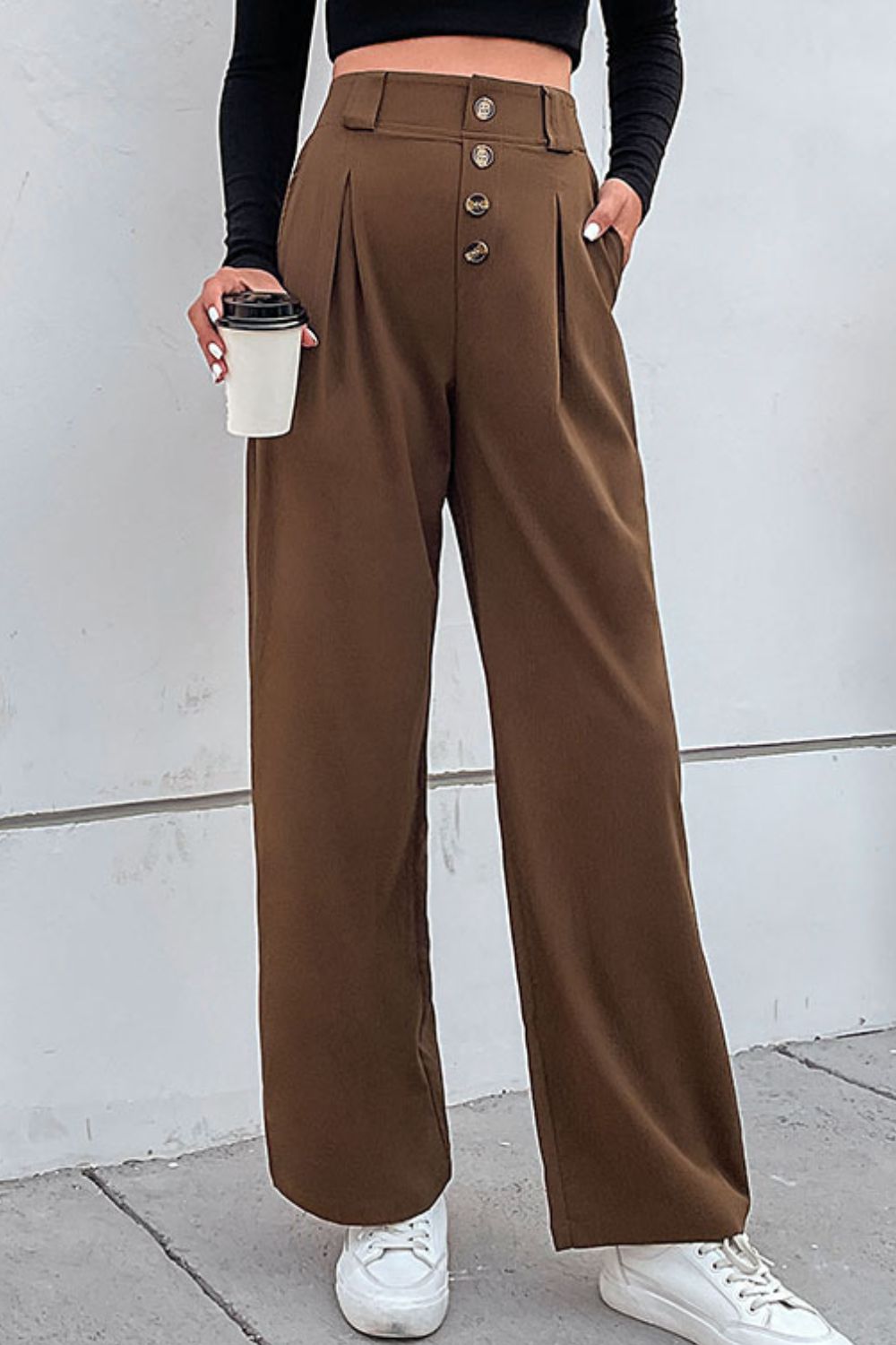 Brown high-waisted tailored wide-leg trousers with button front and pleats.