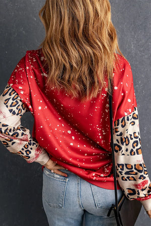 Deep red sweatshirt with white speckle print and leopard print sleeves.