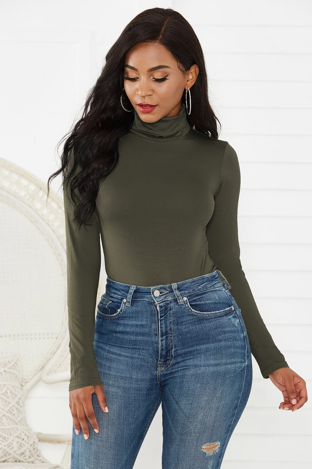 Army green turtleneck bodysuit with long sleeves, paired with distressed denim jeans.