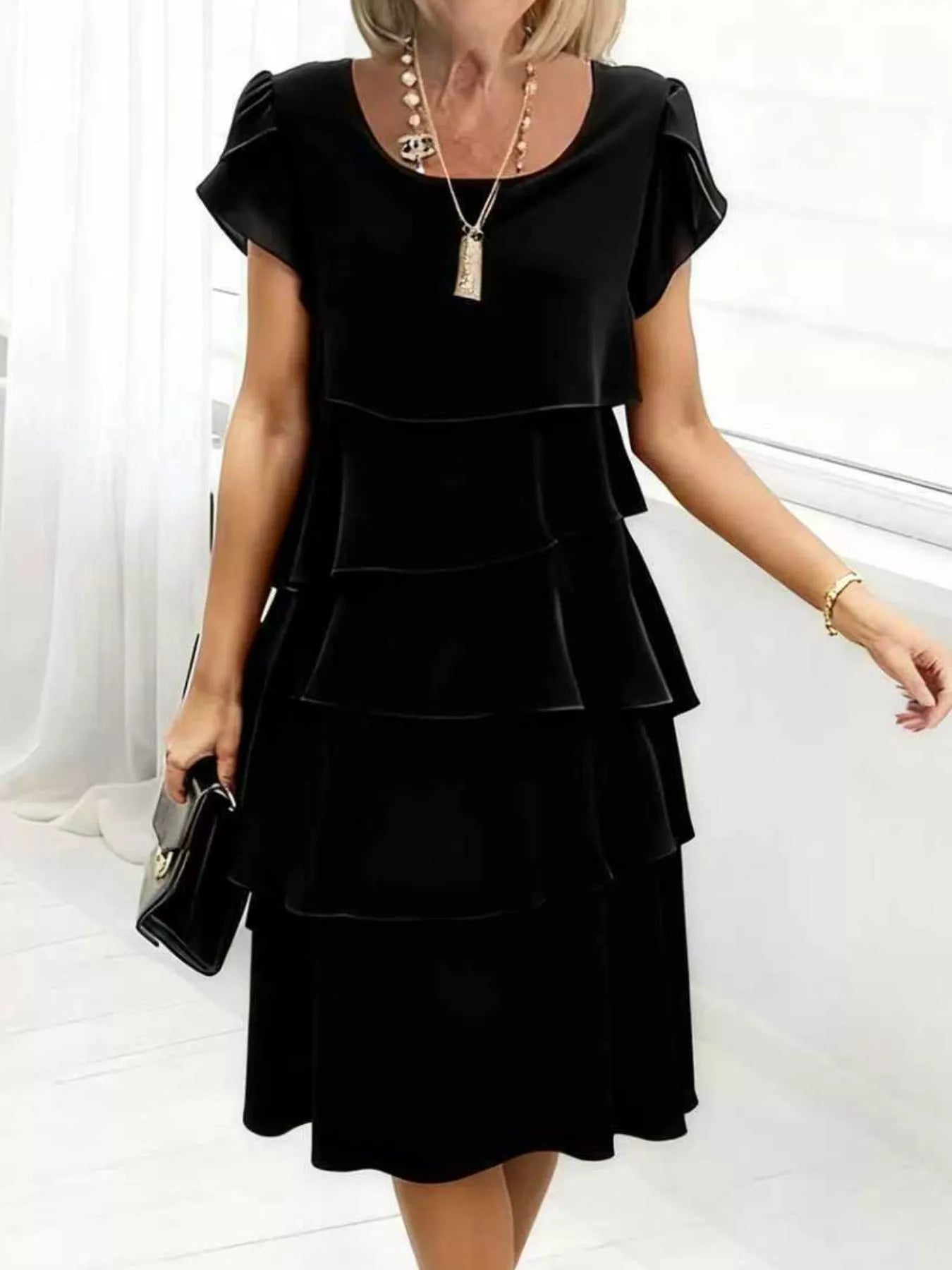 Black tiered petal sleeve dress with ruffled layers and a round neckline.