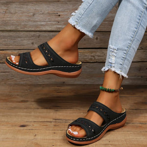 Black embroidered strap comfort slides with cutout details and white stitching.