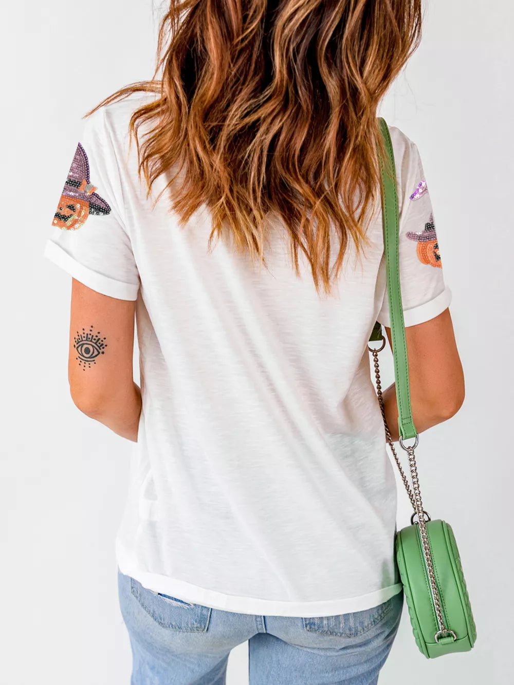White cotton t-shirt with sparkling pumpkin witch graphics on sleeves.