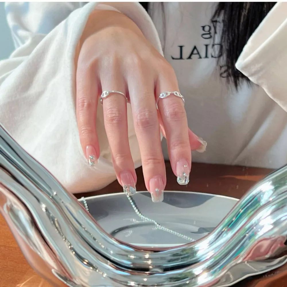 Sleek sterling silver geometric ring with chain-link detail, worn on a woman's finger.