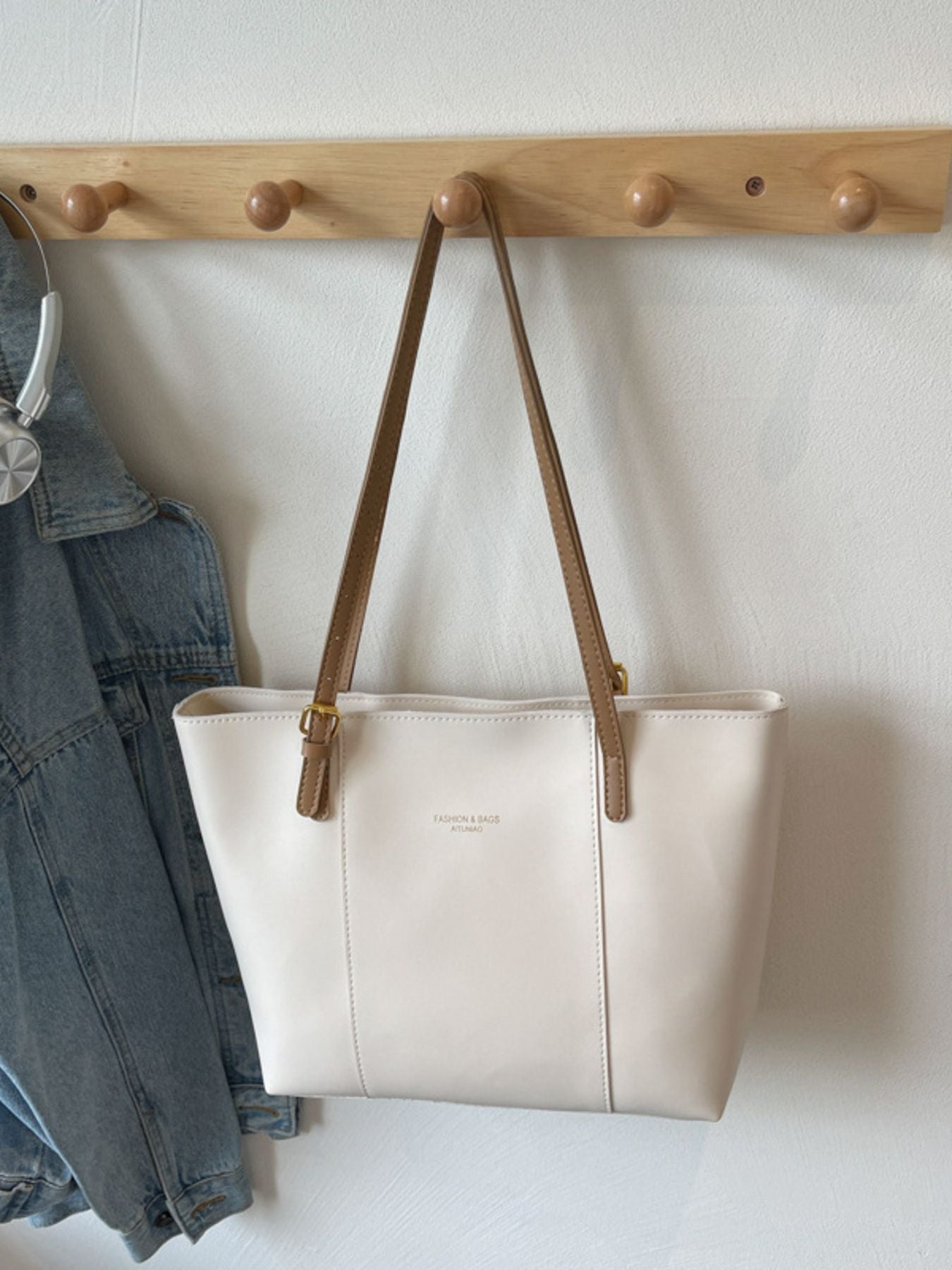 White structured tote bag with brown trim and gold hardware, faux leather.