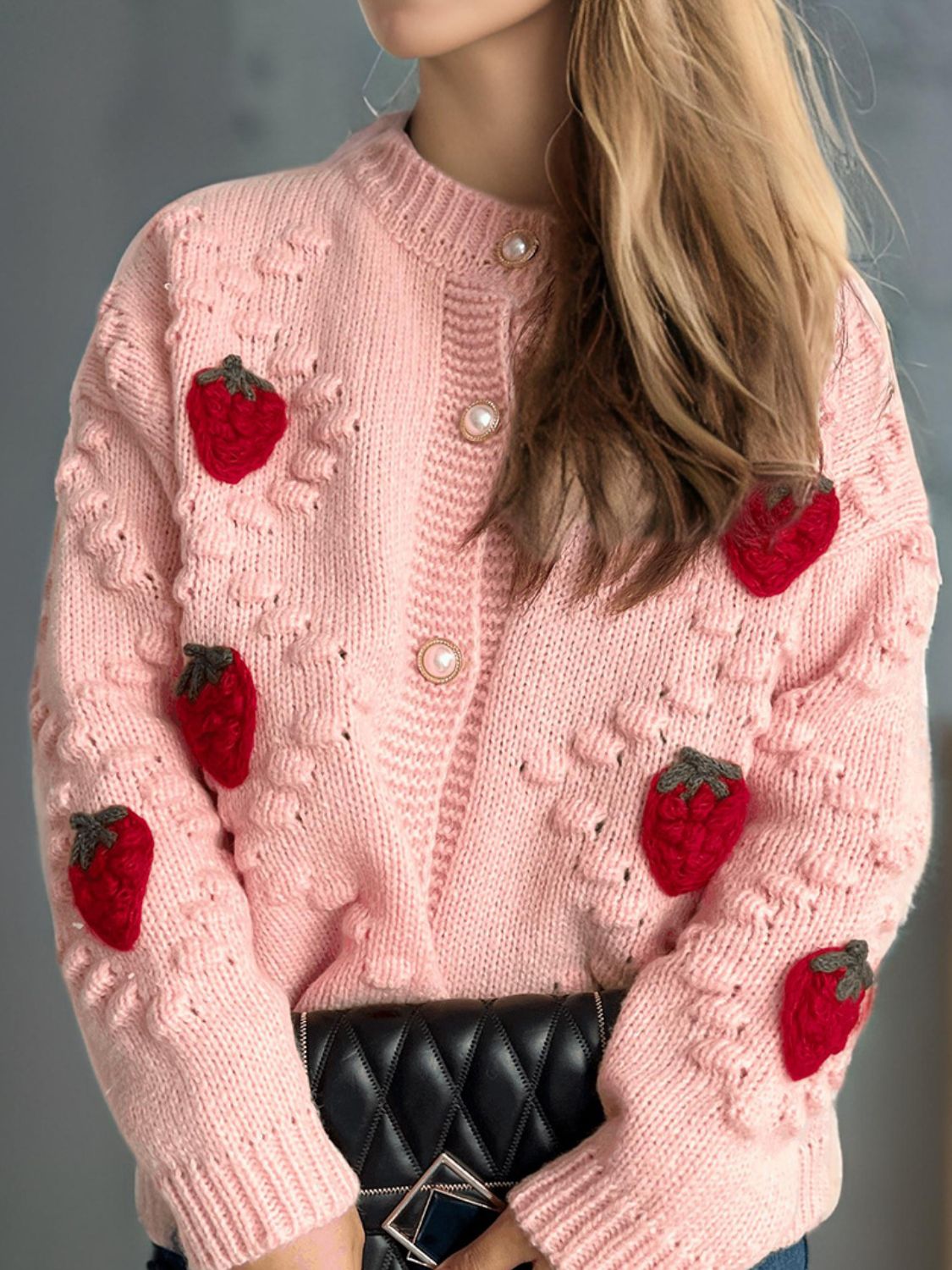 Pink knit cardigan with strawberry appliques and pearl buttons.