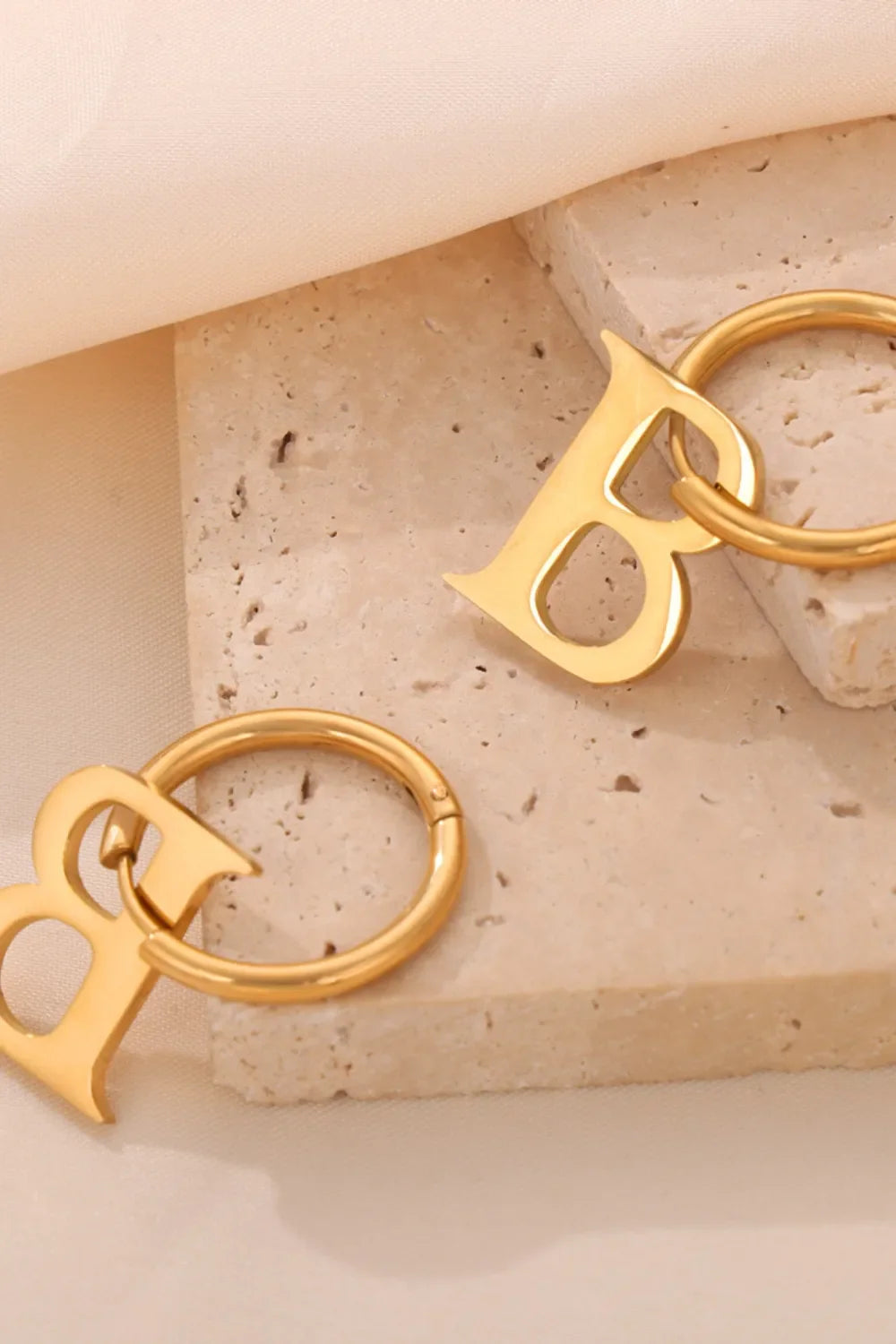 Gold initial letter hoop earrings with a modern design.