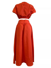 Orange crop top with puff sleeves and elastic hem paired with a high-waisted maxi skirt.