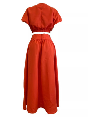 Orange crop top with puff sleeves and elastic hem paired with a high-waisted maxi skirt.