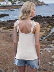 White knit tank top with tie straps and deep V-neck, styled with denim shorts.