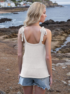 White knit tank top with tie straps and deep V-neck, styled with denim shorts.