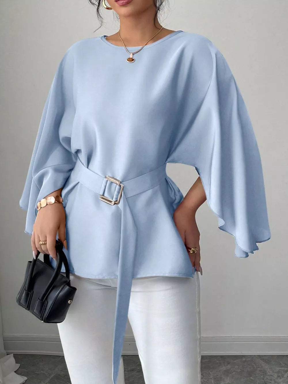 Light blue belted blouse with batwing sleeves and gold buckle detail.