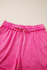 Acid-washed hot pink cotton drawstring shorts with pockets and elastic waistband.