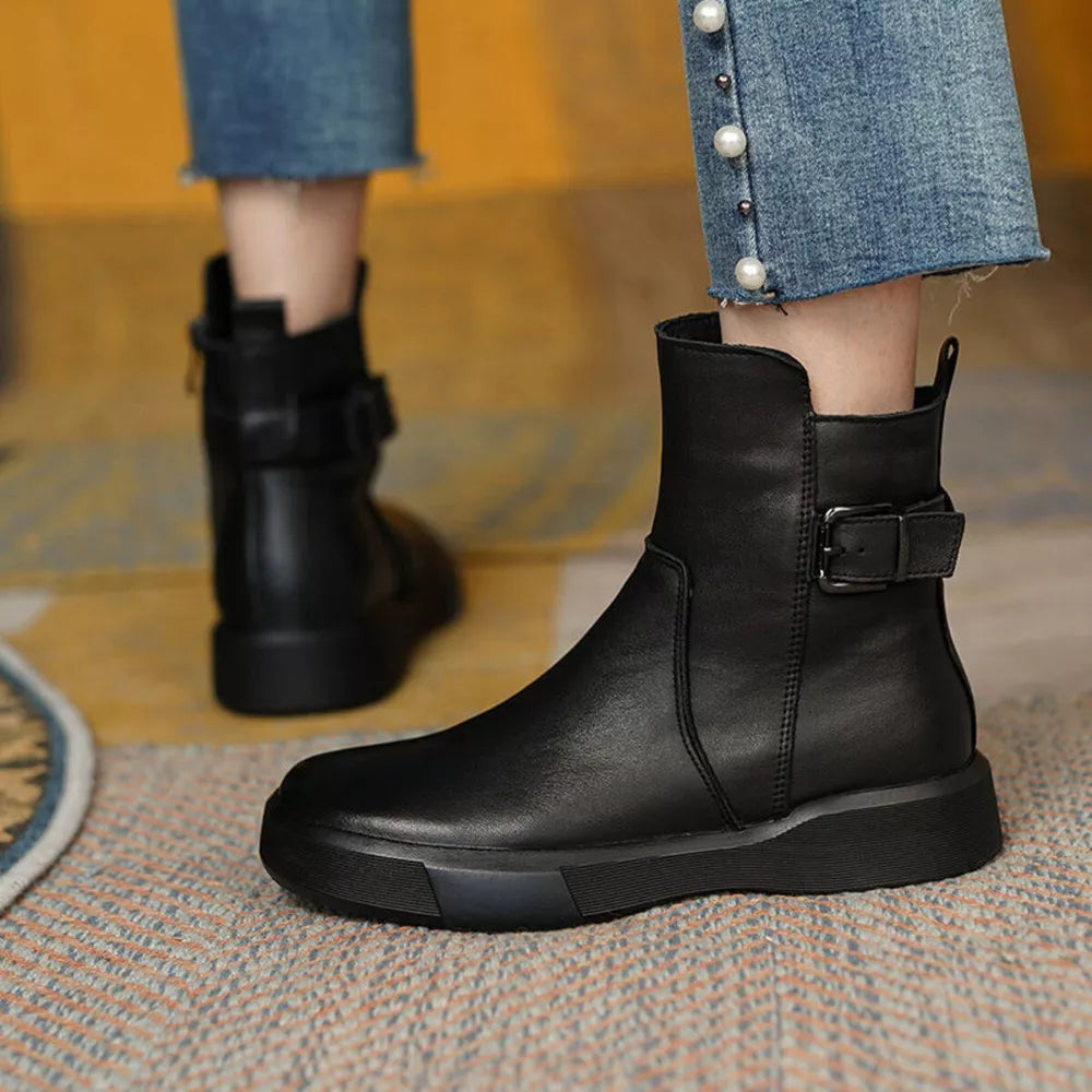 Black leather ankle boots with round toe, platform sole, and decorative buckle detail.
