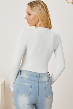 White ribbed long sleeve bodysuit with plunge neckline, styled with light wash jeans.