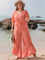 Coral viscose jumpsuit with lace sleeves and hem, tie-front detail, and wide legs.