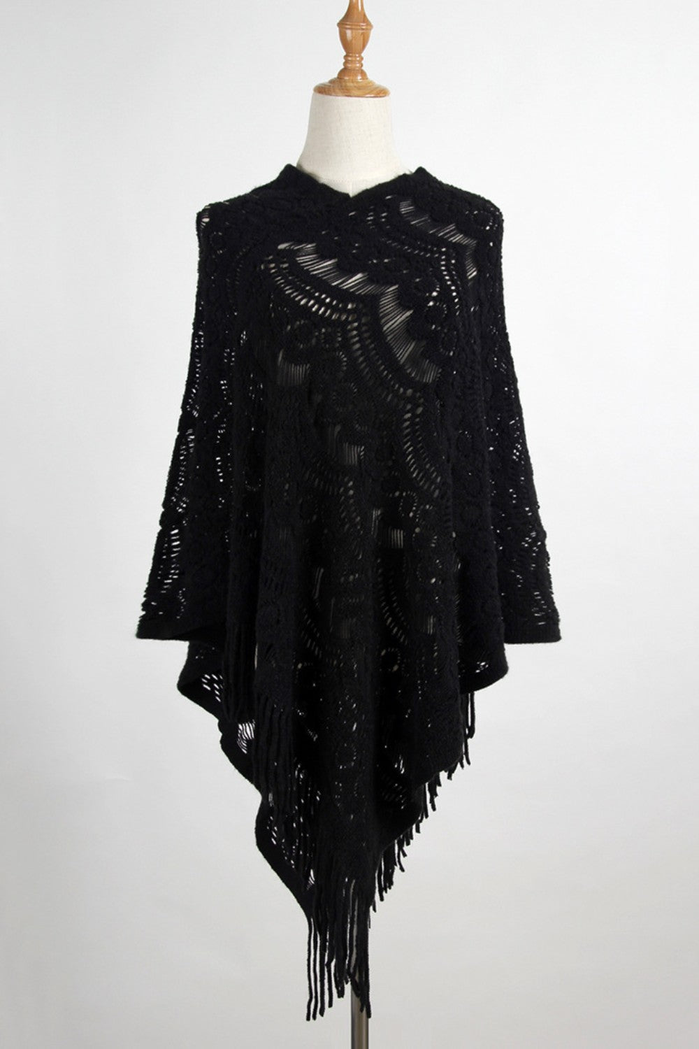 Black crochet poncho with intricate openwork pattern and fringe trim.