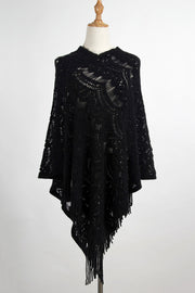 Black crochet poncho with intricate openwork pattern and fringe trim.
