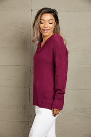 Burgundy knit hooded pullover with fringe trim and textured details.