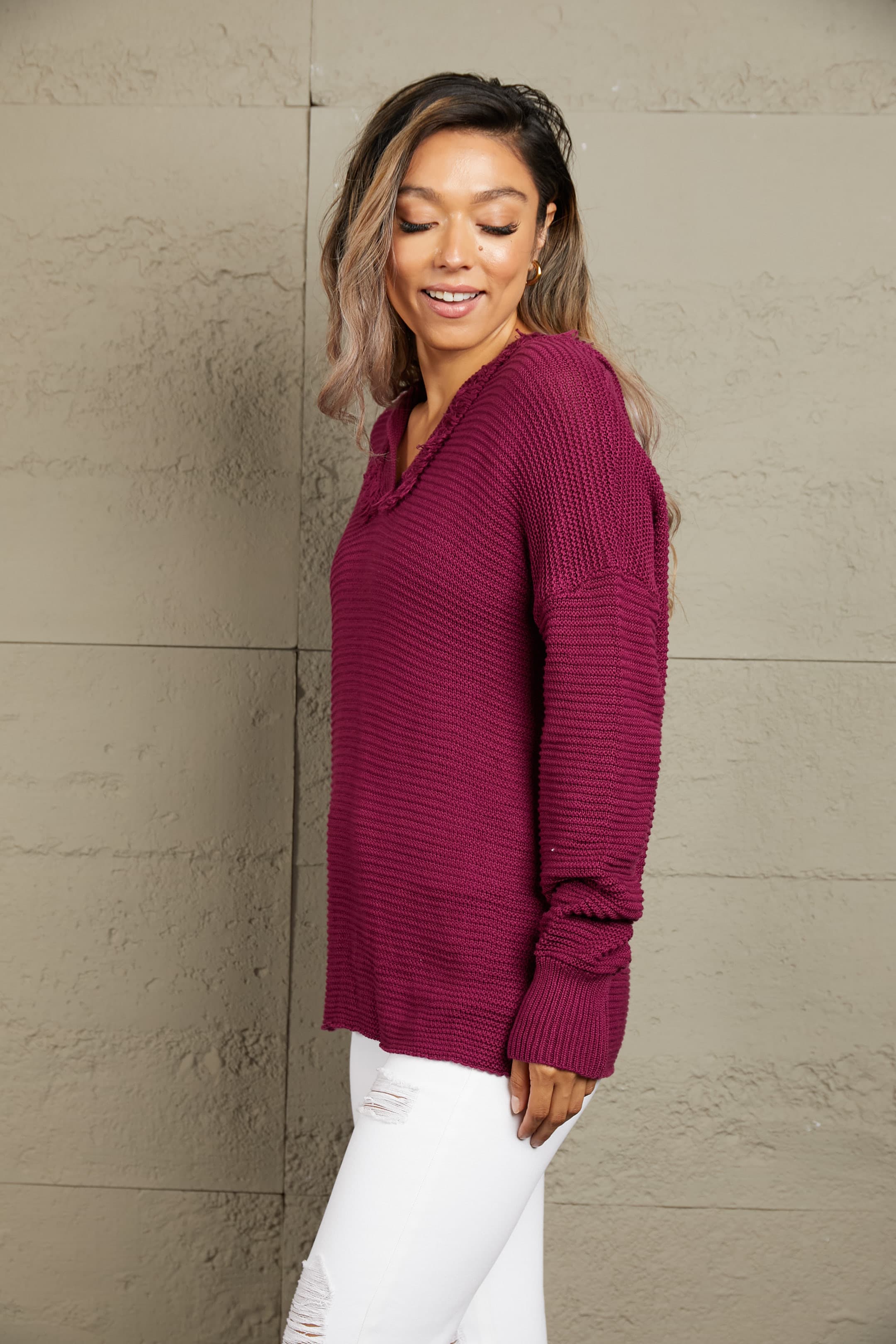 Burgundy knit hooded pullover with fringe trim and textured details.