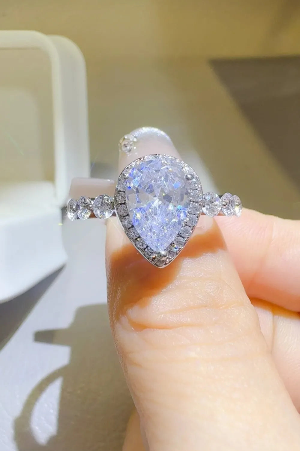 Silver pear-cut moissanite halo ring with accent stones on band