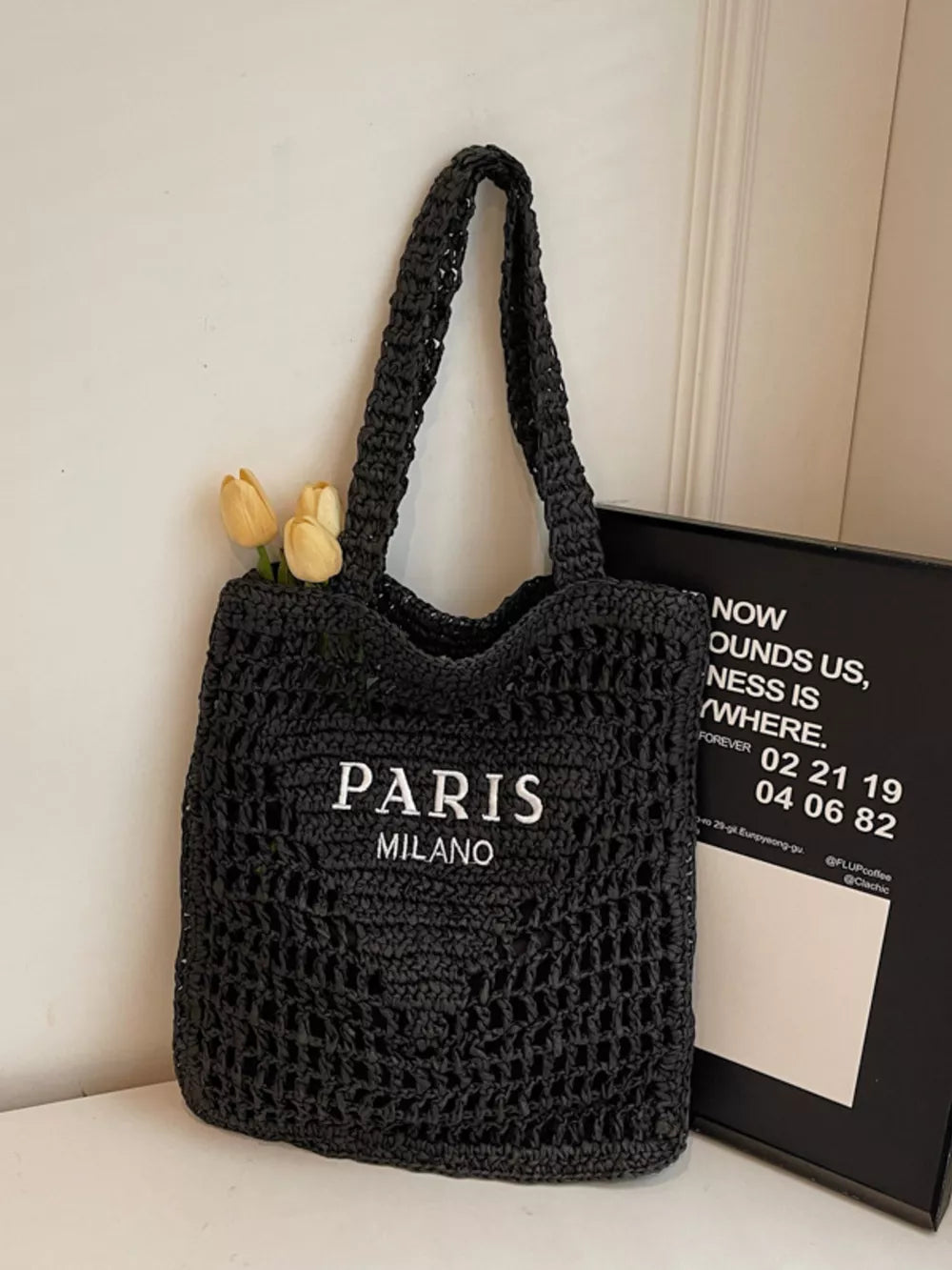 Black crochet tote bag with PARIS MILANO print and yellow tulips.