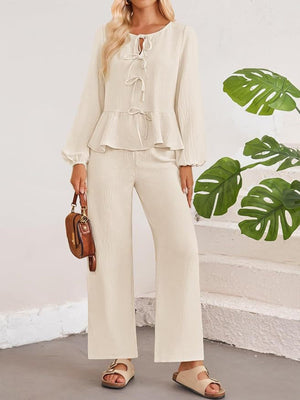 Cream textured peplum tie-neck co-ord set with balloon sleeves and wide-leg pants.