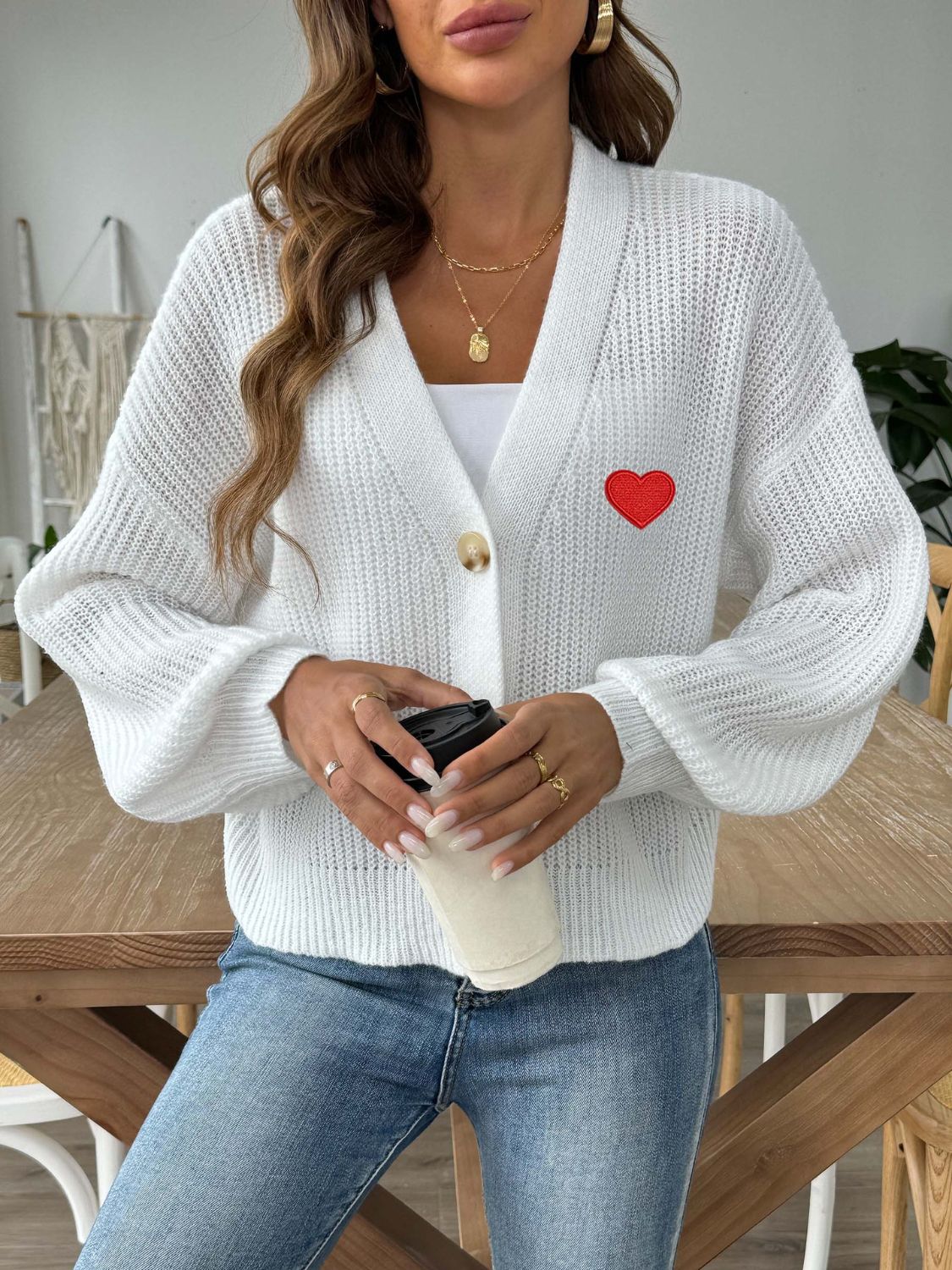 White balloon sleeve cardigan with red heart appliqué and button front.