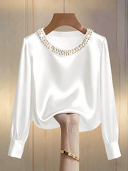 White satin blouse with pearl trim round neckline and long sleeves.
