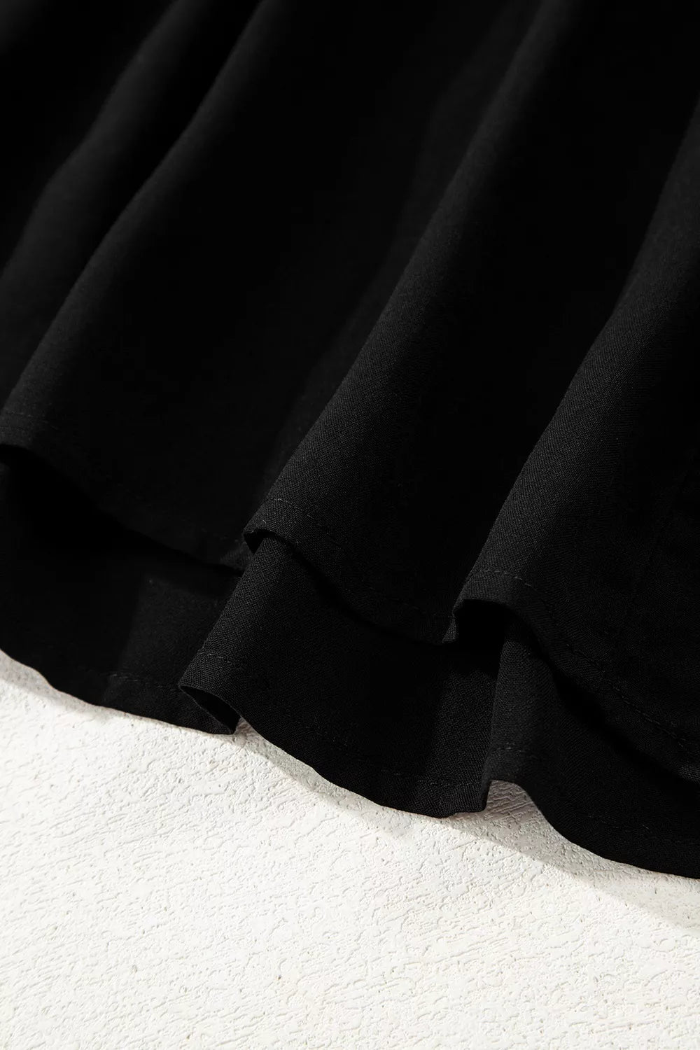 Black tiered maxi dress detail showing fabric texture and hemline