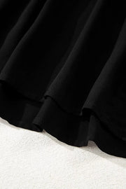 Black tiered maxi dress detail showing fabric texture and hemline