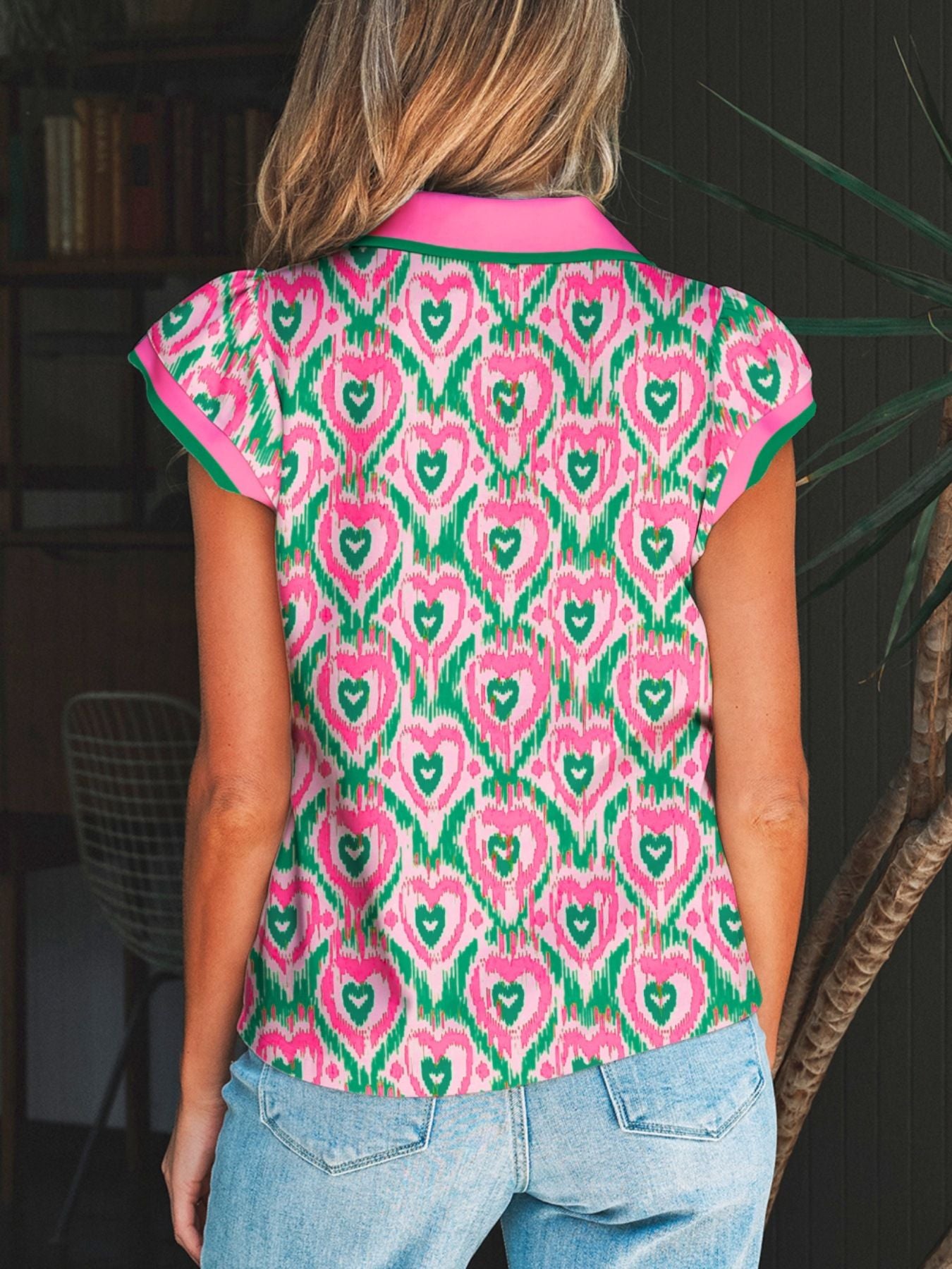 Abstract heart print polo blouse with pink collar and trim, short sleeves, and elastane.
